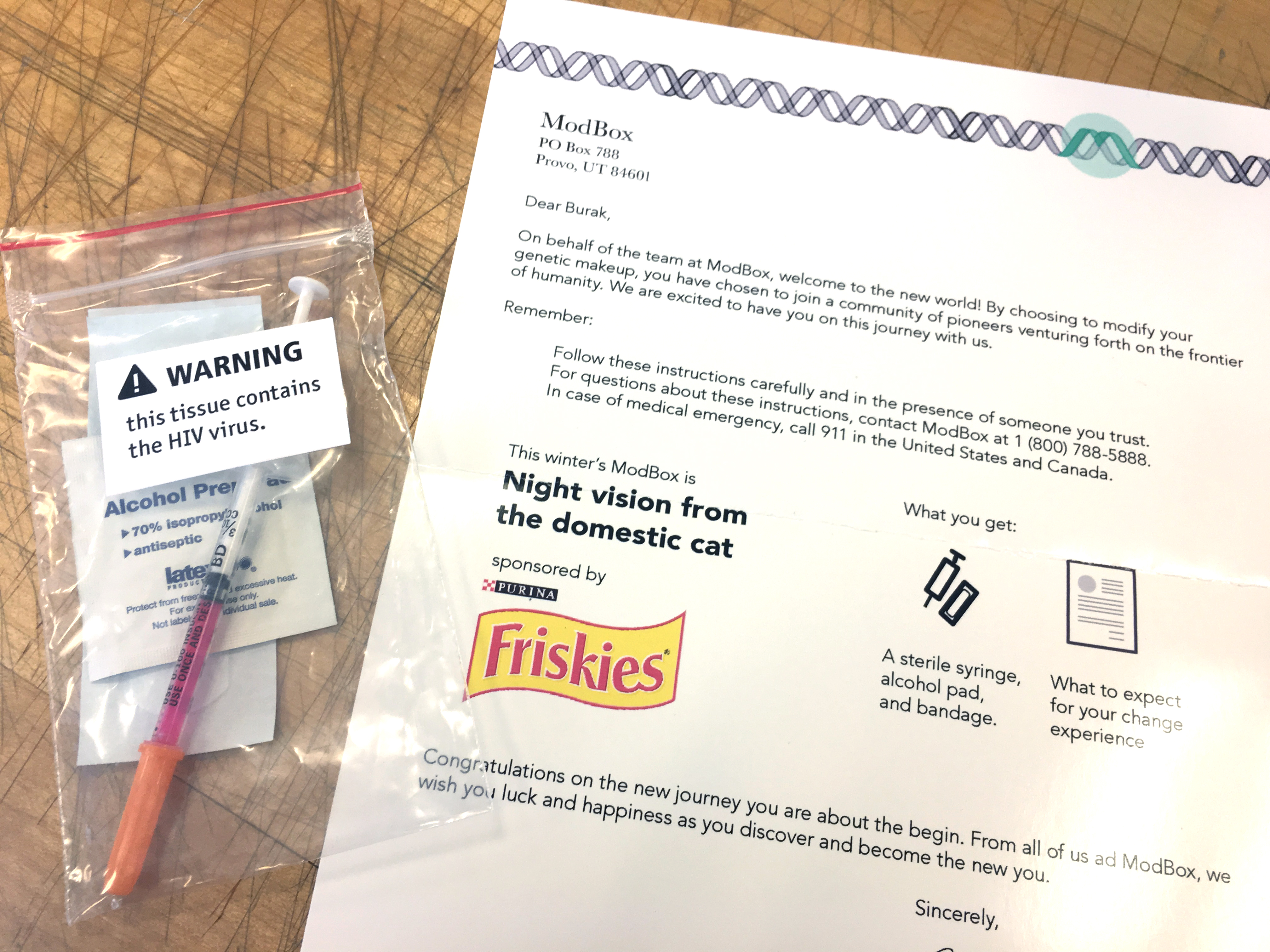 A letter welcomes another customer to the frontier of humanity with supplies to genetically modify a human with night vision from the domestic cat. It's sponsored by Friskies. There is a syringe that contains the HIV virus, how the genetic modifcation is delivered.